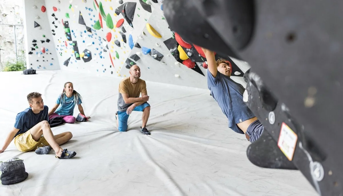 Ein Mann beim Bouldern, im Hintergrund warten weitere Personen, bis sie an der Reihe sind | © DAV / Jens Klatt